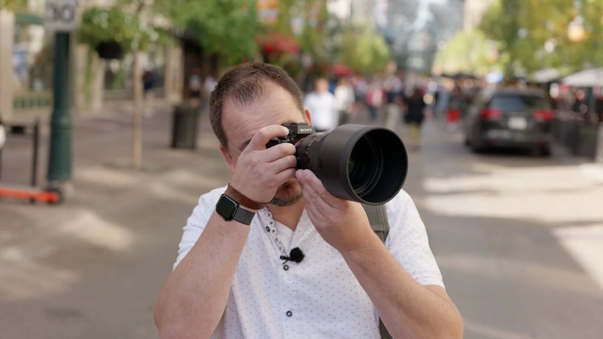 Фотограф держит Sigma 135mm f/1.4 DG Art на камере двумя руками, видны размер и вес объектива при съёмке с рук
